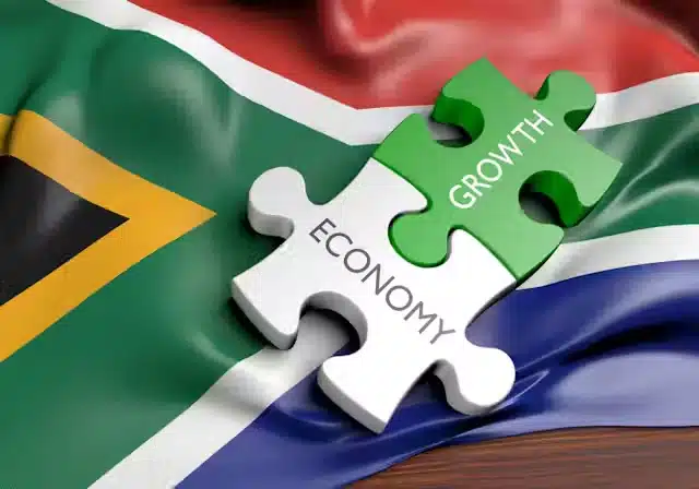 Two interlocking puzzle pieces, one labelled "Economy" and the other "Growth," resting on a gently waving South African flag, symbolising the connection between economic progress and national development.