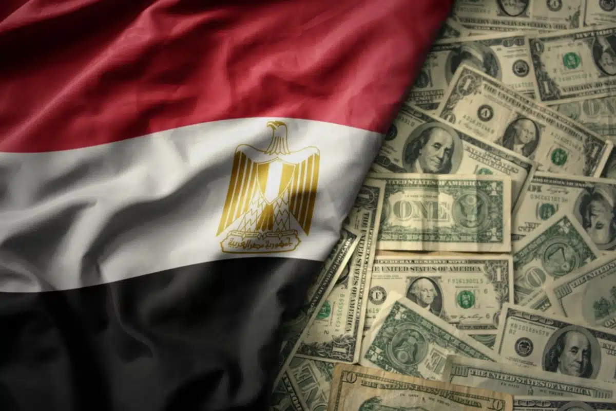 A partially folded Egyptian flag lying beside scattered U.S dollar bills, symbolising Egypt's recent surge in foreign direct investments