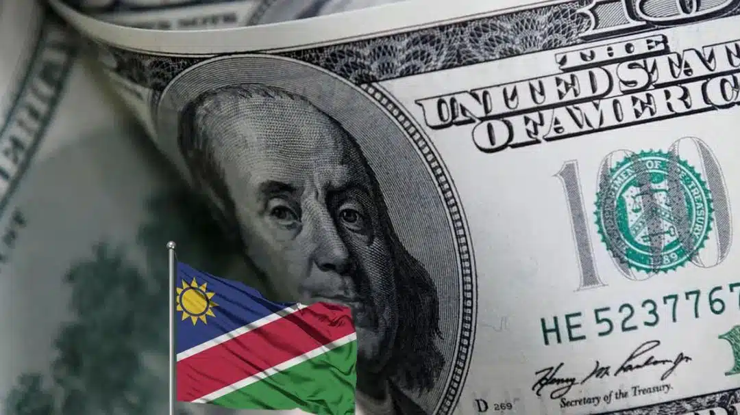 A Namibian flag on a pole placed on an image of a close-up shot of 100 dollar bills