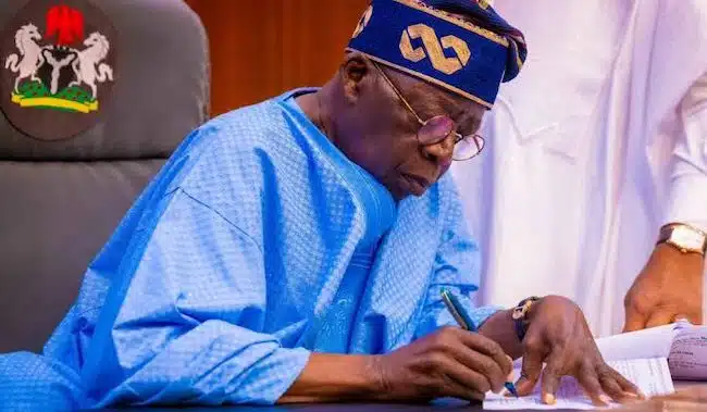An image of President Bola Tinubu signing a document.