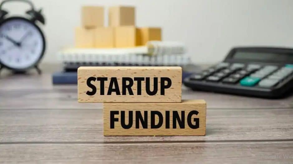 The image shows two wooden blocks stacked on top of each other with the words โSTARTUP FUNDINGโ printed in bold black letters.