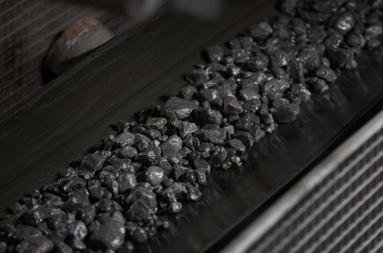 Raw nickel ore being transported on a conveyor belt.